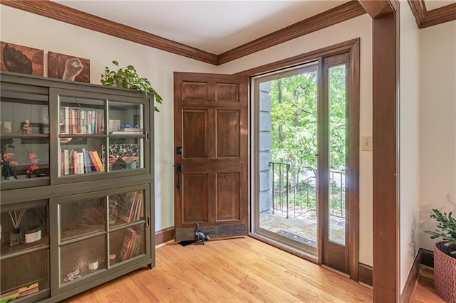 doorway to outside featuring crown molding, baseboards, and light wood finished floors