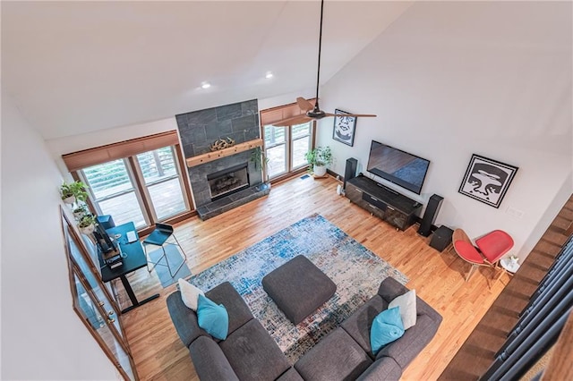 living area featuring a large fireplace, plenty of natural light, a ceiling fan, and wood finished floors