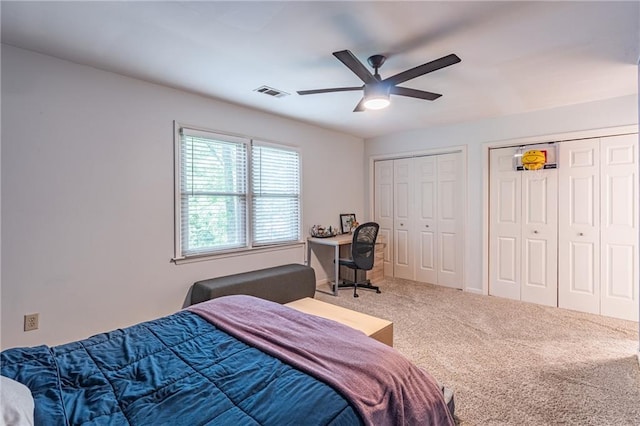 bedroom with carpet floors, a ceiling fan, multiple closets, and visible vents