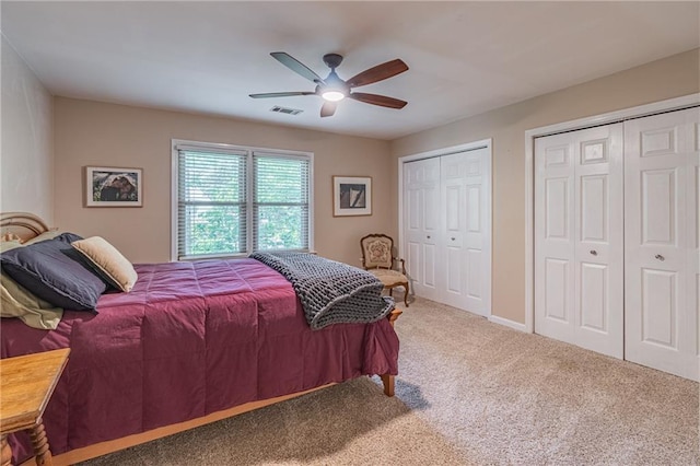 bedroom with carpet flooring, multiple closets, a ceiling fan, baseboards, and visible vents