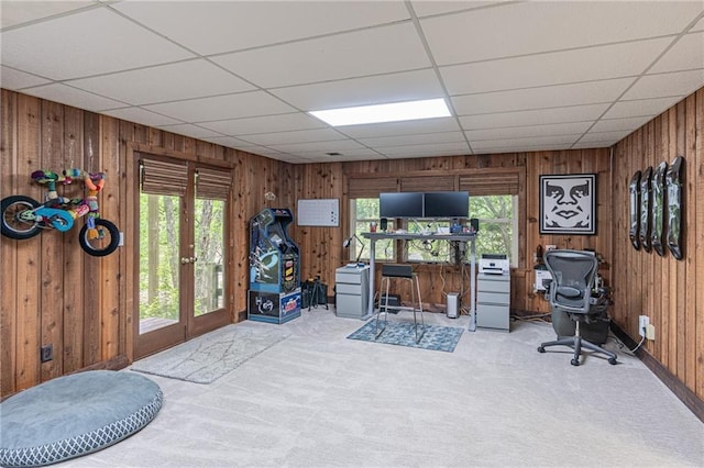 home office with french doors, carpet, wooden walls, and a paneled ceiling