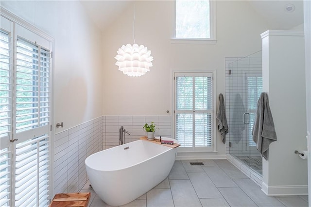 bathroom with tile patterned floors, a shower stall, a wealth of natural light, and high vaulted ceiling