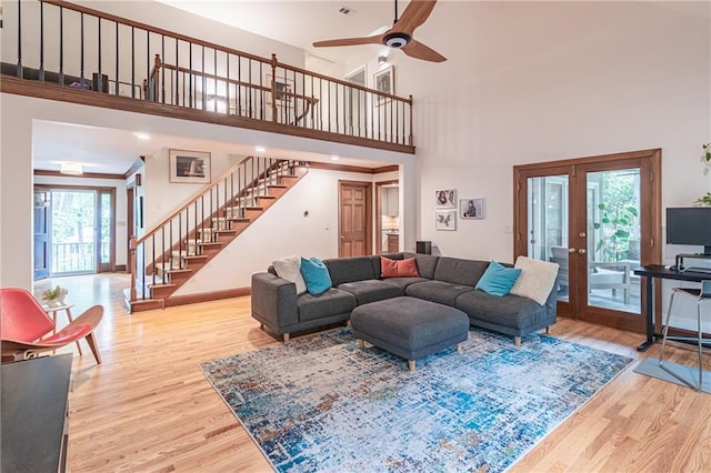 living area featuring french doors, ceiling fan, wood finished floors, and stairway