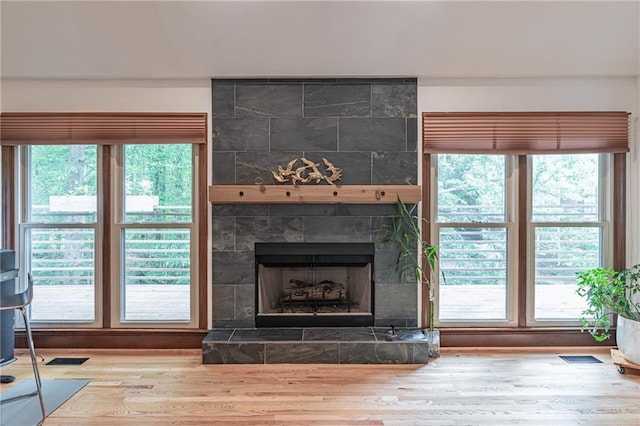 interior space with a wealth of natural light, wood finished floors, and a tile fireplace