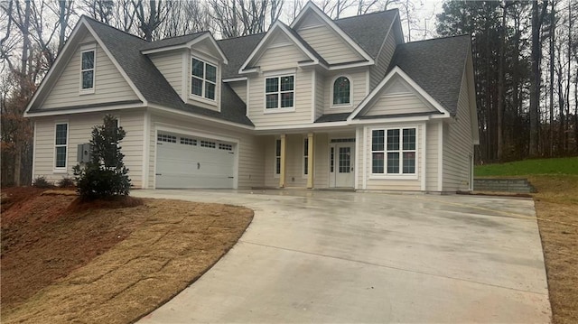 view of front facade with a garage, concrete driveway, and roof with shingles