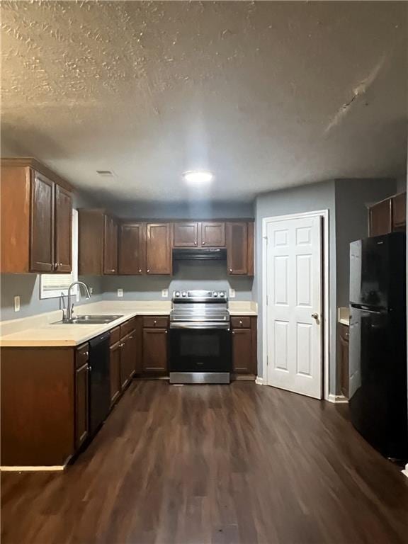 kitchen featuring black appliances, a sink, extractor fan, light countertops, and dark wood-style floors