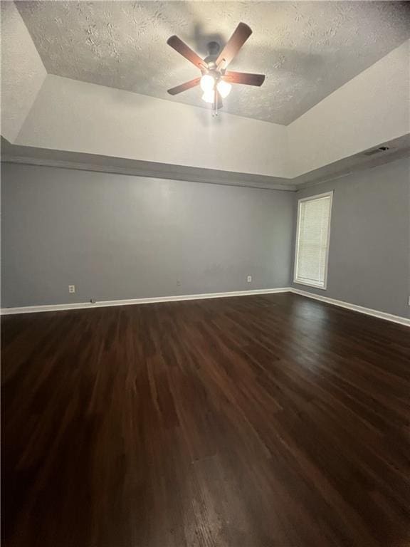 spare room with wood finished floors, a textured ceiling, baseboards, and lofted ceiling