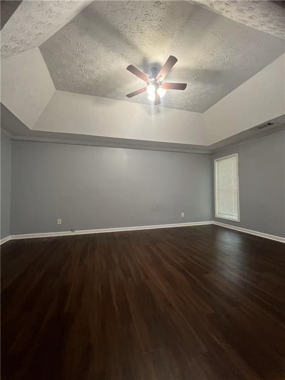 spare room featuring dark wood-style floors, a ceiling fan, baseboards, a textured ceiling, and lofted ceiling