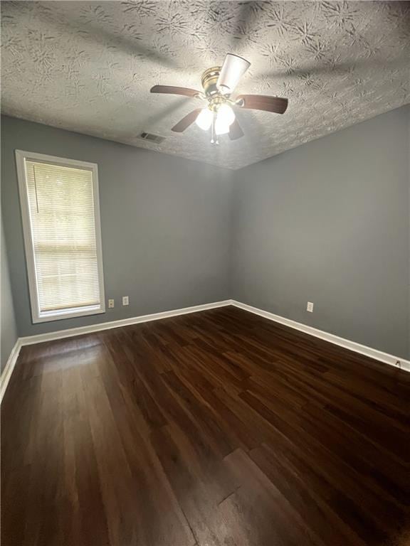 unfurnished room with dark wood-style flooring, a ceiling fan, baseboards, and a textured ceiling