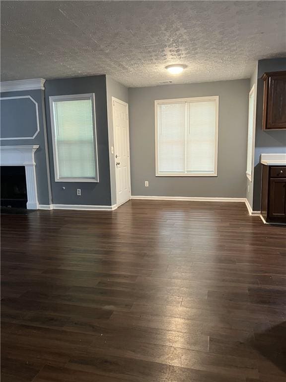 unfurnished living room with a textured ceiling, baseboards, dark wood-style floors, and a fireplace
