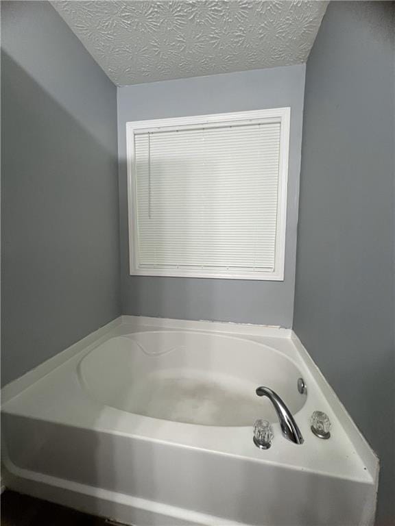 full bathroom with a bath and a textured ceiling