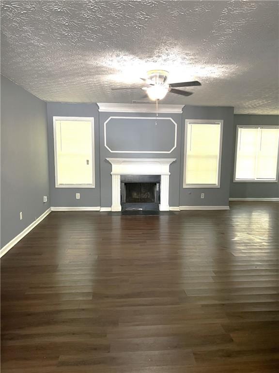 unfurnished living room with a ceiling fan, baseboards, wood finished floors, a fireplace, and a textured ceiling