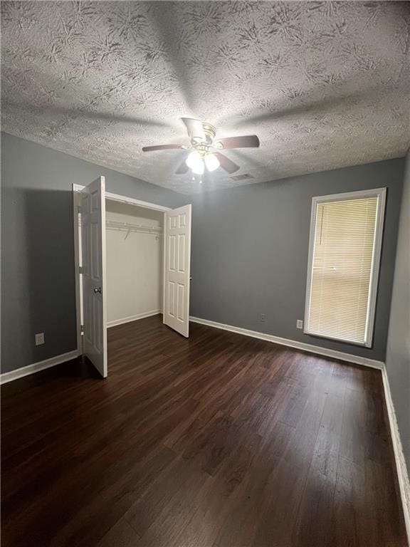 unfurnished bedroom with dark wood-style flooring, baseboards, a closet, ceiling fan, and a textured ceiling