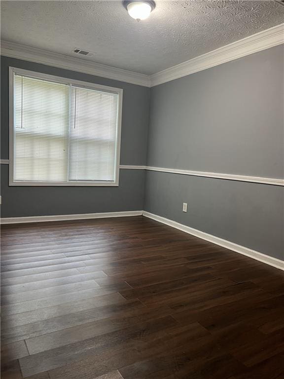 unfurnished room featuring dark wood-type flooring, a textured ceiling, ornamental molding, and baseboards