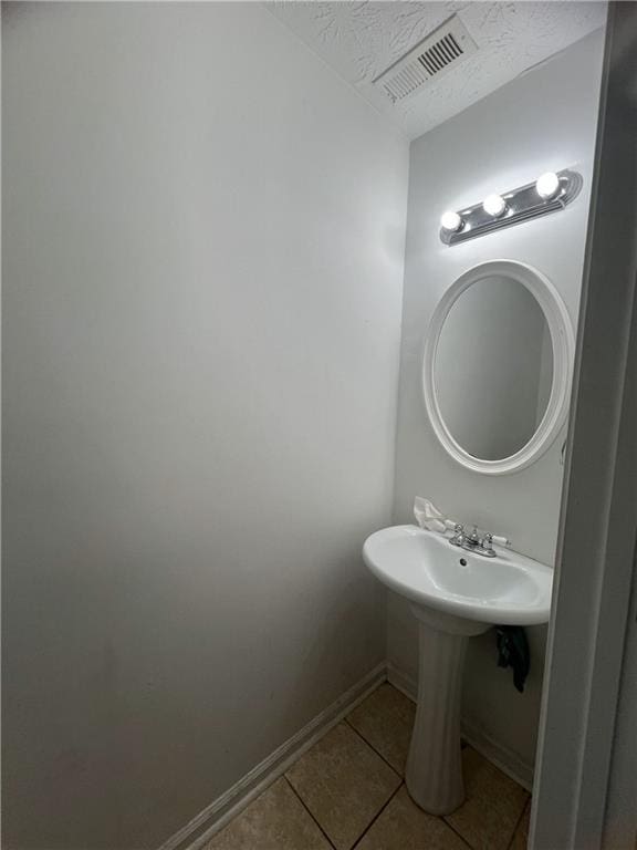 bathroom with tile patterned floors, baseboards, a textured ceiling, and a sink