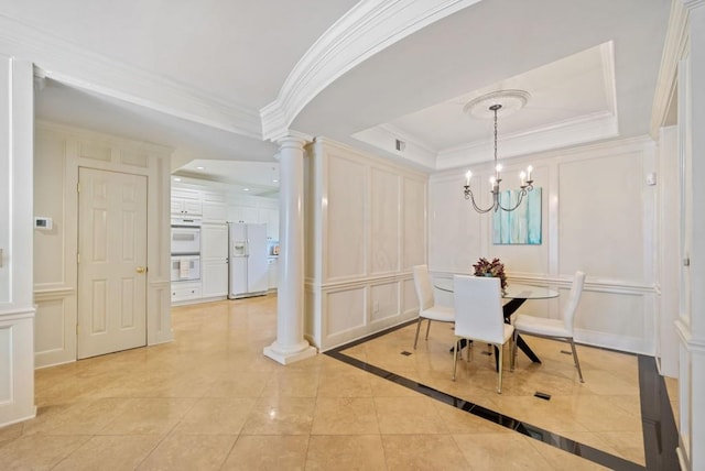 dining area with a notable chandelier, ornamental molding, a raised ceiling, and ornate columns