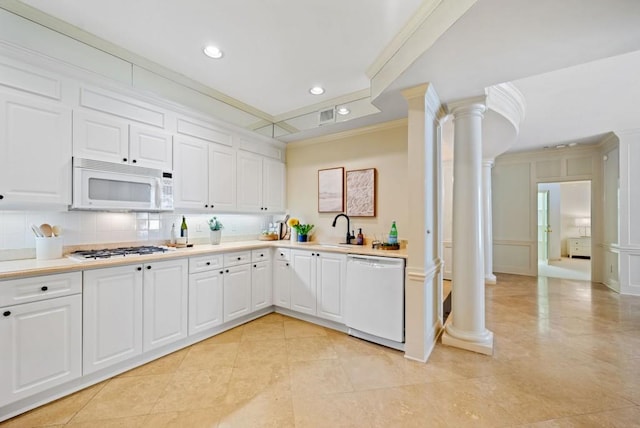 kitchen featuring sink, dishwasher, white cabinetry, built in shelves, and ornate columns