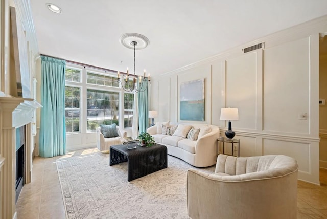 living room with a tiled fireplace, built in features, ornamental molding, and a chandelier