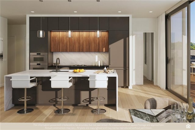 kitchen featuring light wood-style floors, modern cabinets, a breakfast bar, appliances with stainless steel finishes, and a sink