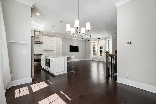 kitchen with white cabinets, a kitchen island, decorative light fixtures, wall chimney exhaust hood, and dark hardwood / wood-style flooring