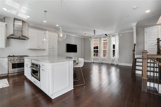 kitchen with appliances with stainless steel finishes, wall chimney exhaust hood, and white cabinets