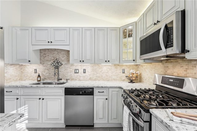 10475 Willow Meadow Cir, Alpharetta, GA 30022 - kitchen featuring appliances with stainless steel finishes, lofted ceiling, decorative backsplash, light stone counters, and glass insert cabinets