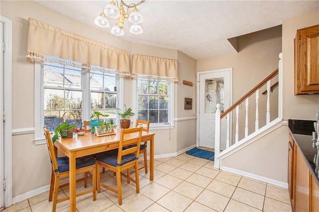 dining space featuring light tile patterned flooring, a textured ceiling, and a notable chandelier