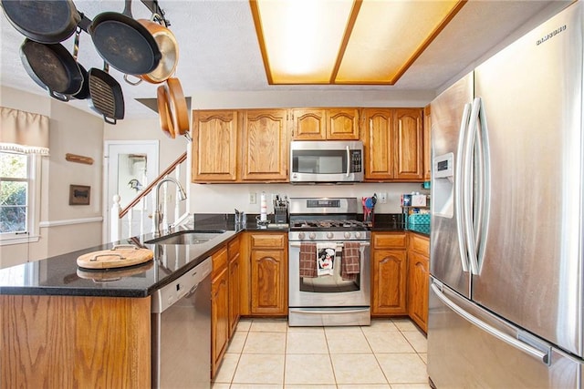 kitchen featuring sink, stainless steel appliances, dark stone counters, and light tile patterned flooring