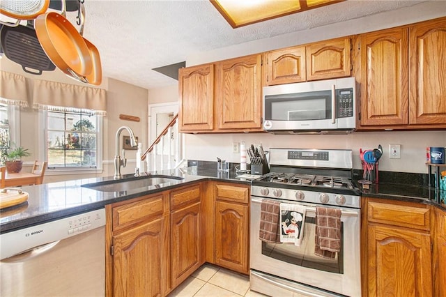 kitchen with sink, light tile patterned floors, stainless steel appliances, and a textured ceiling