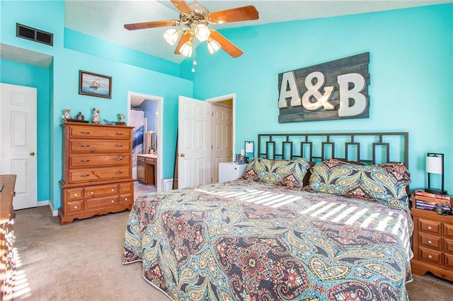 bedroom with ceiling fan, carpet flooring, vaulted ceiling, and ensuite bath