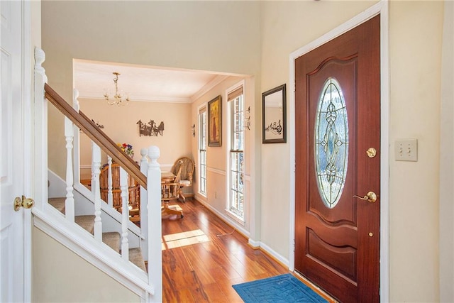 foyer entrance with hardwood / wood-style flooring, ornamental molding, plenty of natural light, and a notable chandelier