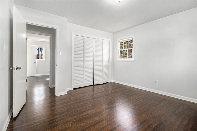 unfurnished bedroom with dark hardwood / wood-style floors and a closet