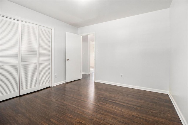 unfurnished bedroom featuring a closet and dark wood-type flooring