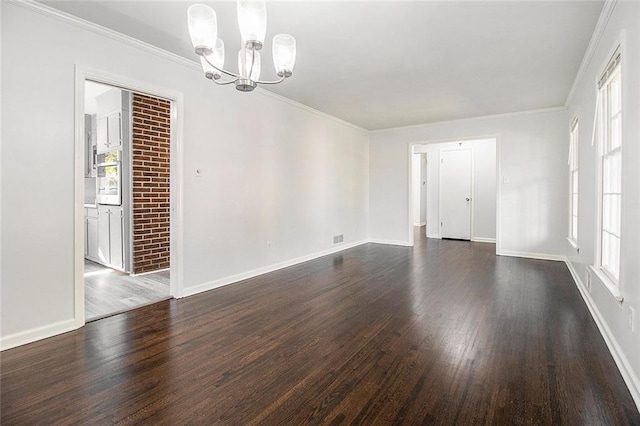 empty room with a chandelier, crown molding, and dark wood-type flooring