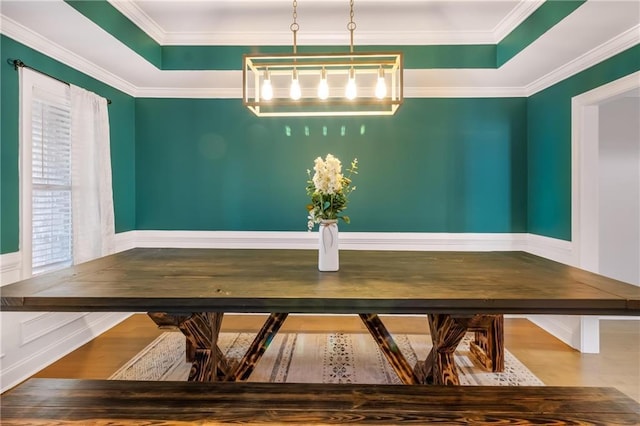 unfurnished dining area featuring hardwood / wood-style floors, a tray ceiling, and ornamental molding