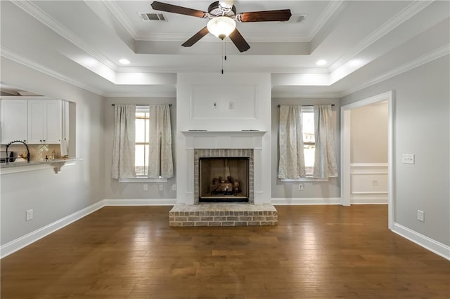 unfurnished living room featuring dark hardwood / wood-style flooring, crown molding, a fireplace, and a raised ceiling