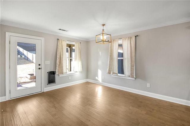 empty room featuring a notable chandelier, hardwood / wood-style flooring, and ornamental molding