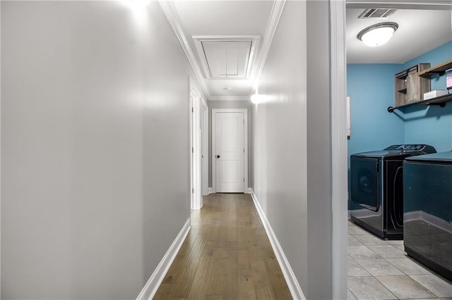 hallway with crown molding, independent washer and dryer, and light hardwood / wood-style floors