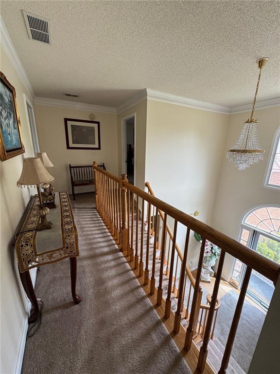 2246 Carrington Dr, Ellenwood, GA 30294 - hall with a textured ceiling, visible vents, a notable chandelier, and an upstairs landing