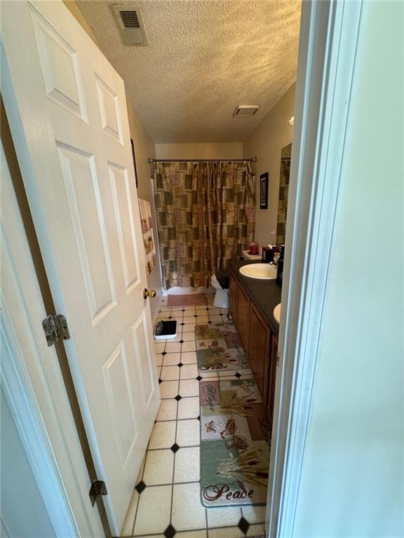 2246 Carrington Dr, Ellenwood, GA 30294 - full bath with a textured ceiling, vanity, toilet, tile patterned flooring, and visible vents