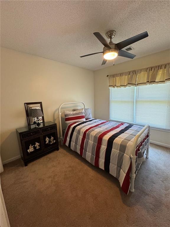 2246 Carrington Dr, Ellenwood, GA 30294 - carpeted bedroom featuring ceiling fan, a textured ceiling, and visible vents