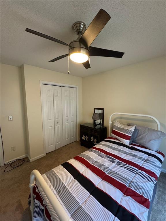 2246 Carrington Dr, Ellenwood, GA 30294 - carpeted bedroom with a textured ceiling, a closet, and a ceiling fan