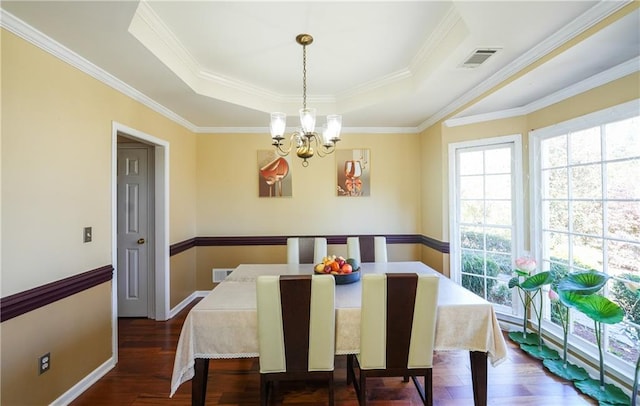 dining space with dark hardwood / wood-style floors, ornamental molding, and a tray ceiling