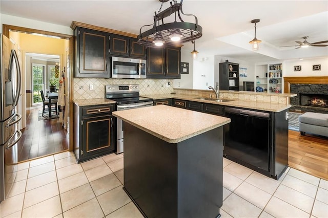 kitchen featuring sink, stainless steel appliances, kitchen peninsula, decorative light fixtures, and light wood-type flooring