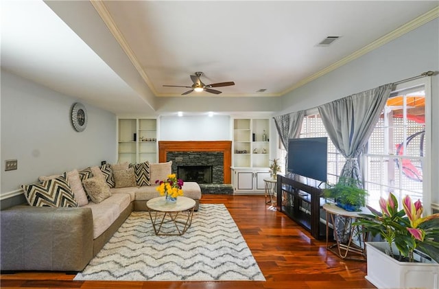 living room with a fireplace, ornamental molding, ceiling fan, and dark wood-type flooring