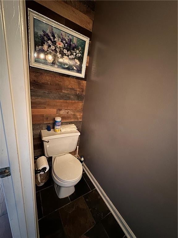 bathroom featuring wood walls and toilet