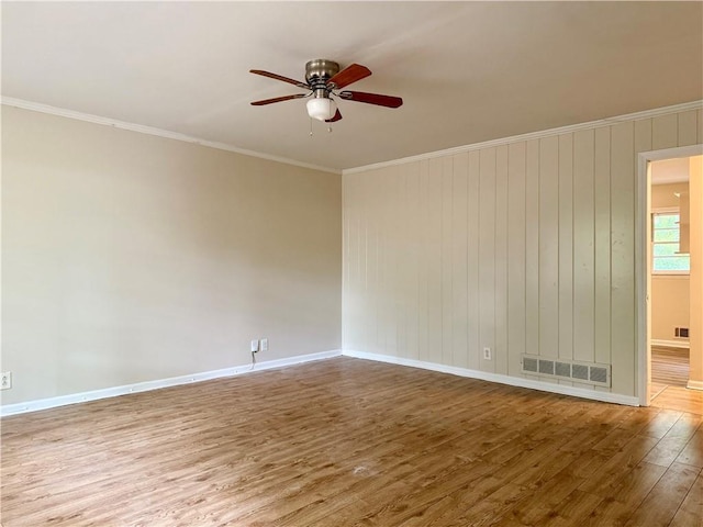 unfurnished room with crown molding, visible vents, baseboards, wood finished floors, and a ceiling fan