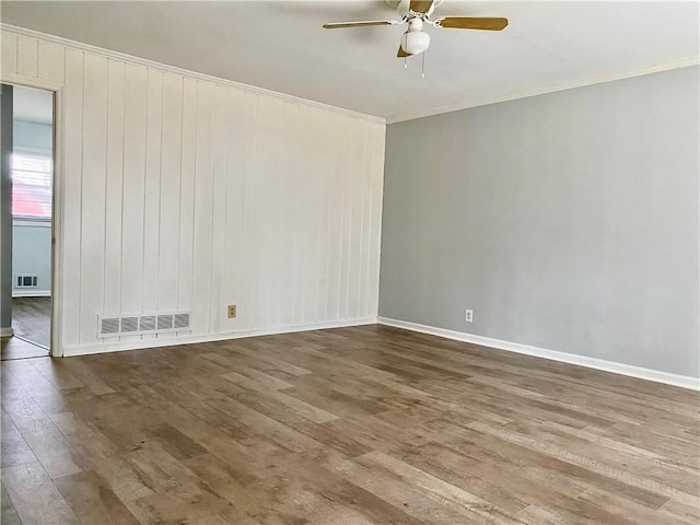 spare room featuring a ceiling fan, visible vents, wood finished floors, and baseboards