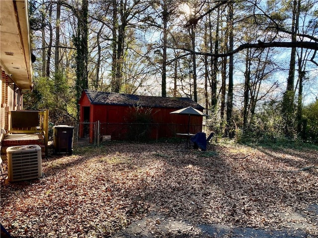 view of yard with an outdoor structure, fence, and central AC unit