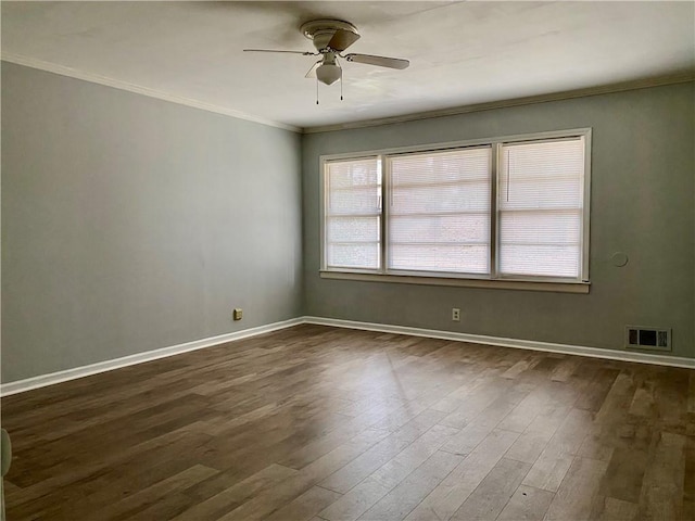 spare room with crown molding, visible vents, ceiling fan, baseboards, and dark wood-type flooring